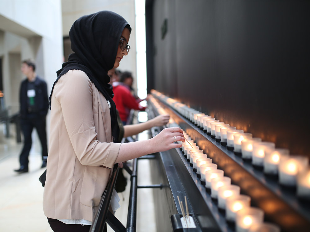 Young woman lights candle at memorial