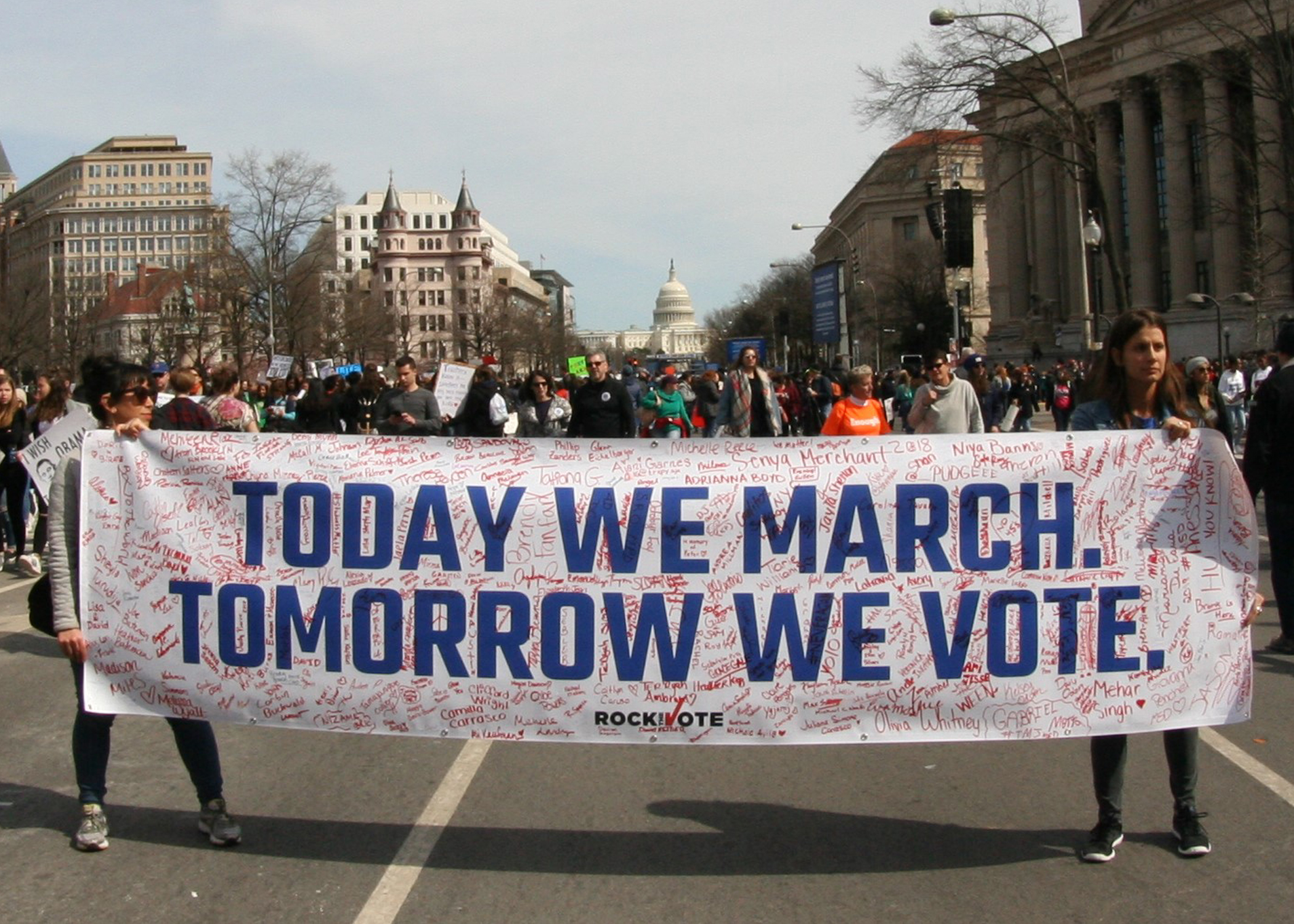 People holding a "Today We March, Tomorrow We Vote" banner during March for Our Lives rally in DC