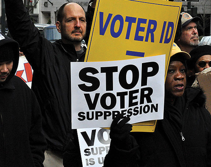 Protestors hold signs "Stop Voter Suppression"