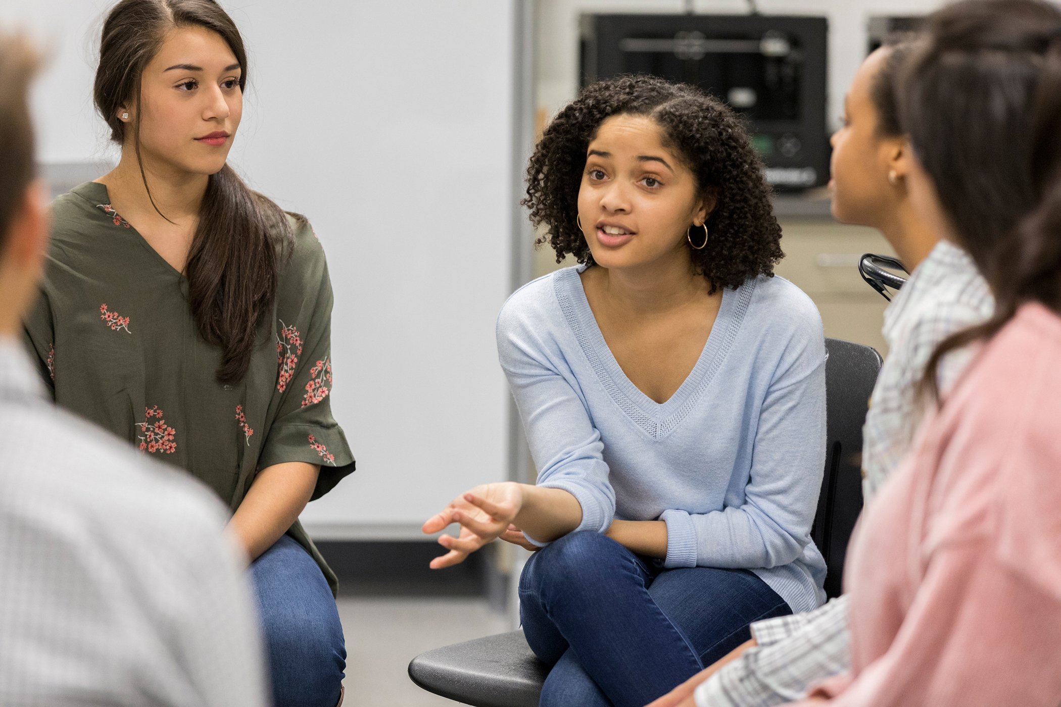 Teenage girl talks during group discussion of a diverse group of teens and adults