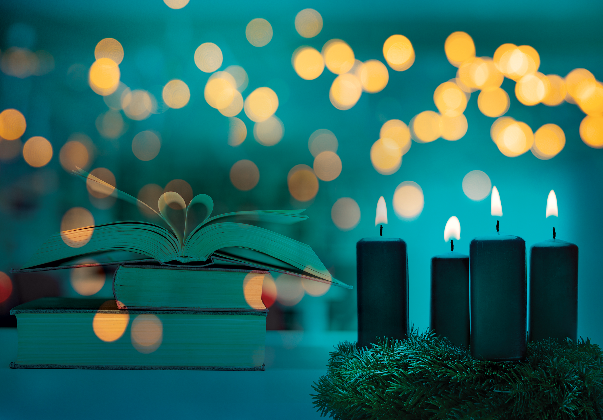 Stack of books on a table behind candles and sparkling lights 