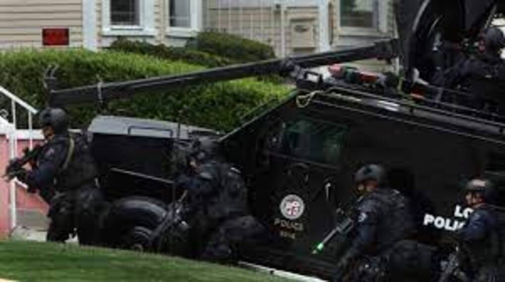 Four armed police officers exiting a SWAT vehicle in a residential neighborhood.