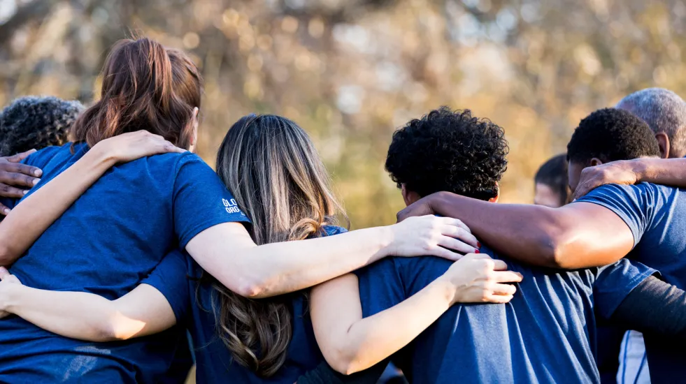 Rearview of friends linking arms in unity