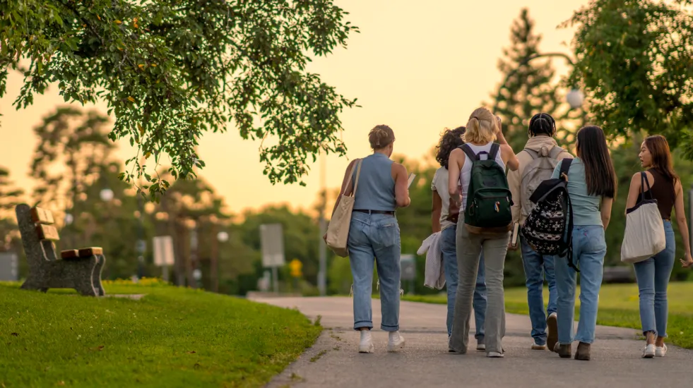 Rearview of university students walking outside on campus