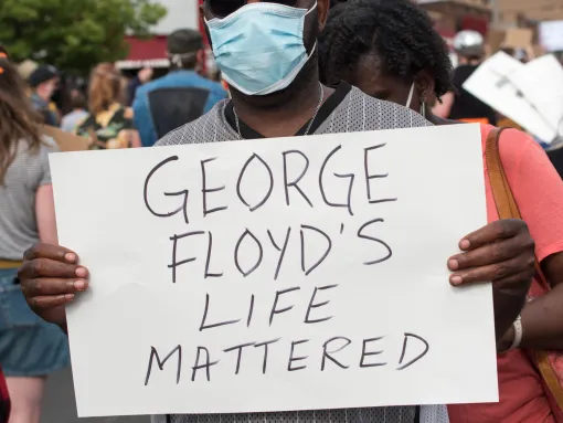Man protesting police violence holding sign that reads "George Floyd's Life Mattered"