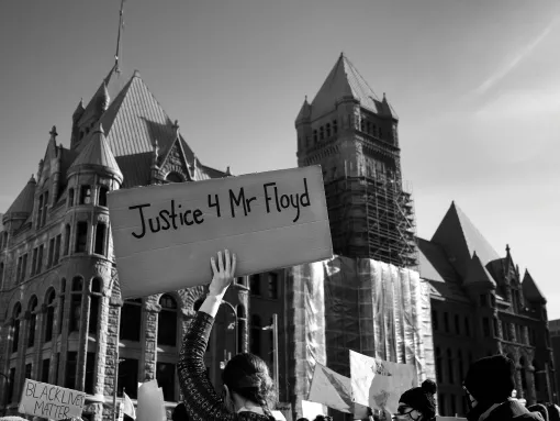 Amongst a crowd of people, a person holds a "Justice 4 Mr. Floyd" sign outside City Hall in downtown Minneapolis