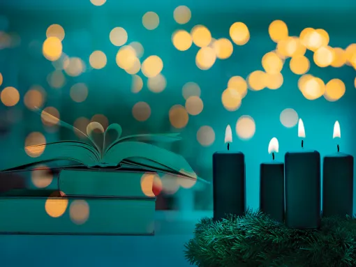 Stack of books on a table behind candles and sparkling lights 