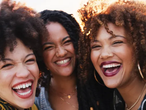 Three ethnic females with natural hair styles laughing together