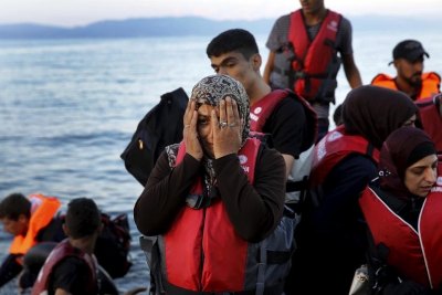 A Syrian refugee woman reacts while travelling in an overcrowded dinghy as it arrives at a beach on the Greek island of Lesbos, after crossing part of the Aegean Sea from Turkey, September 25, 2015.  REUTERS/Yannis Behrakis