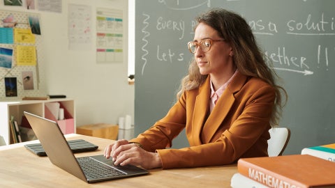 Teacher in a classroom working on a laptop