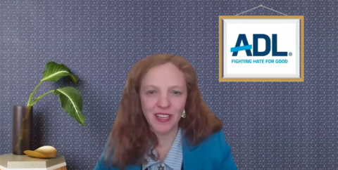 Woman sitting down with a grayish wall background and the ADL logo as a framed picture