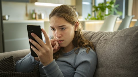 Teen girl looking at phone with concern