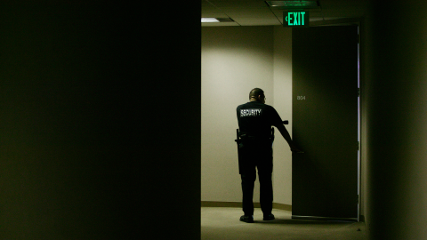 Security Guard with Flashlight Checking Doorway