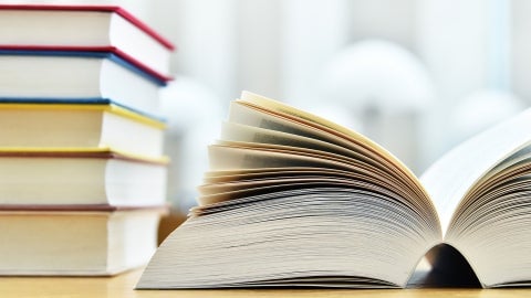 Books stacked on a table with one book lying flat and open